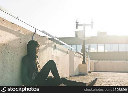 Young woman sitting on sunlit rooftop