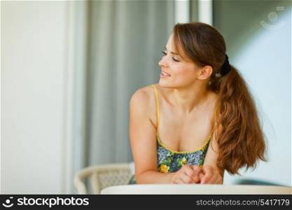 Young woman sitting on terrace and looking on copyspace