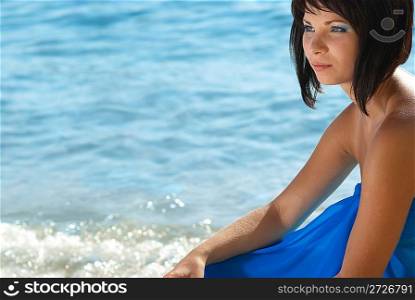 Young woman sitting on th beach with water background