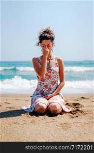 Young woman sitting on the beach in summer dress day practice yoga breathing exercise