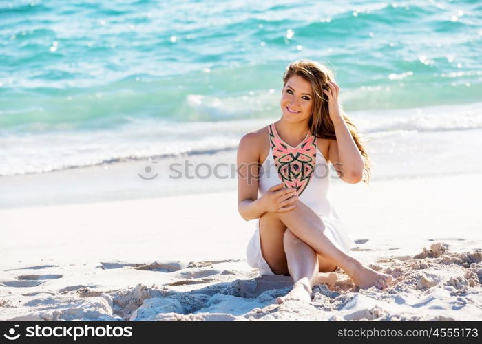 Young woman sitting on the beach. Portrait of young pretty woman sitting on sandy beach