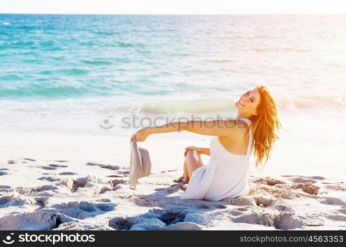 Young woman sitting on the beach. Portrait of young pretty woman sitting on sandy beach