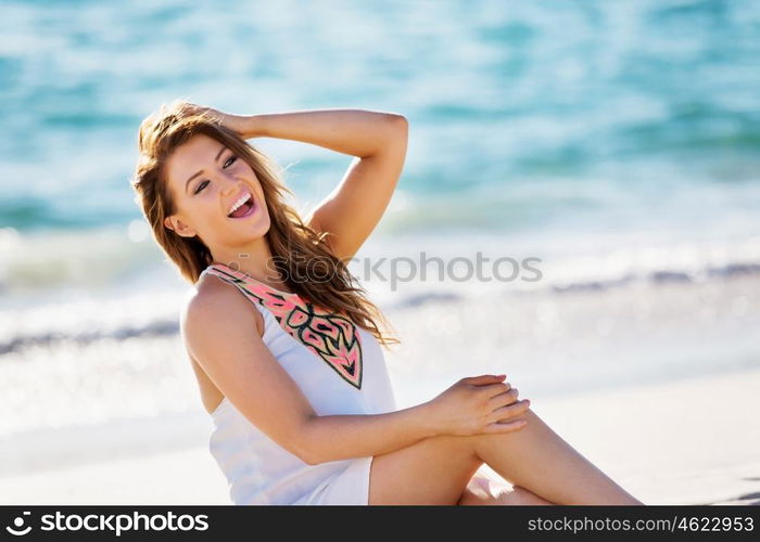 Young woman sitting on the beach. Portrait of young pretty woman sitting on sandy beach