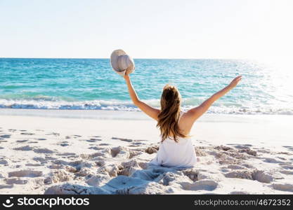 Young woman sitting on the beach. Portrait of young pretty woman sitting on sandy beach