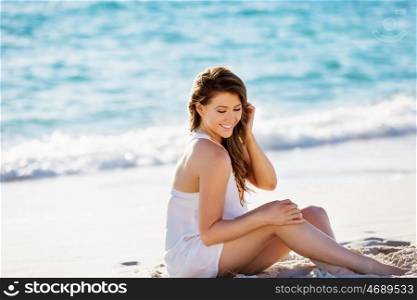 Young woman sitting on the beach. Portrait of young pretty woman sitting on sandy beach