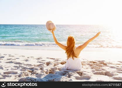 Young woman sitting on the beach. Portrait of young pretty woman sitting on sandy beach