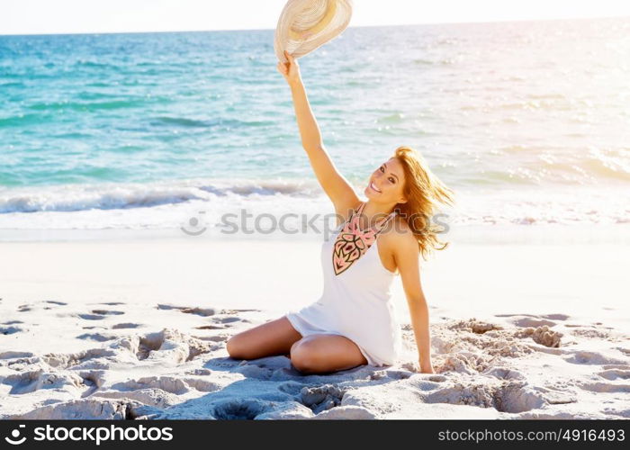 Young woman sitting on the beach. Portrait of young pretty woman sitting on sandy beach