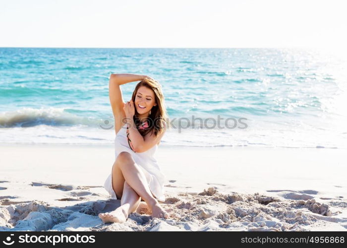 Young woman sitting on the beach. Portrait of young pretty woman sitting on sandy beach