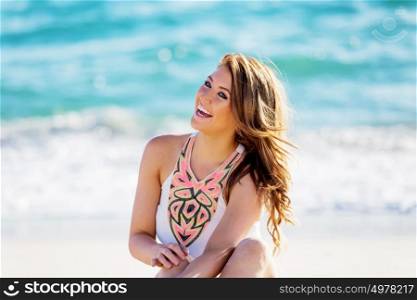Young woman sitting on the beach. Portrait of young pretty woman sitting on sandy beach