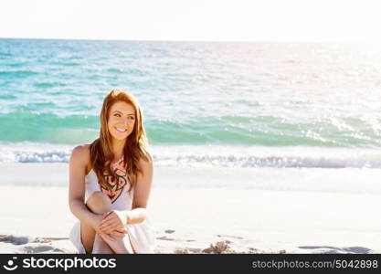 Young woman sitting on the beach. Portrait of young pretty woman sitting on sandy beach