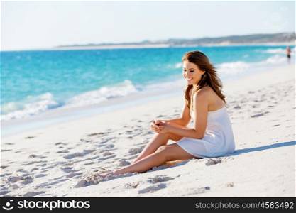 Young woman sitting on the beach. Portrait of young pretty woman sitting on the beach
