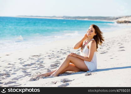 Young woman sitting on the beach. Portrait of young pretty woman sitting on the beach