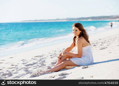 Young woman sitting on the beach. Portrait of young pretty woman sitting on the beach