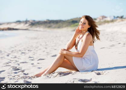 Young woman sitting on the beach. Portrait of young pretty woman sitting on the beach