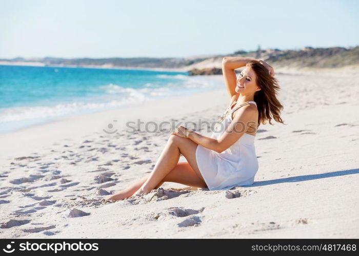 Young woman sitting on the beach. Portrait of young pretty woman sitting on the beach