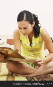 Young woman sitting on the bed and looking at a box of chocolates