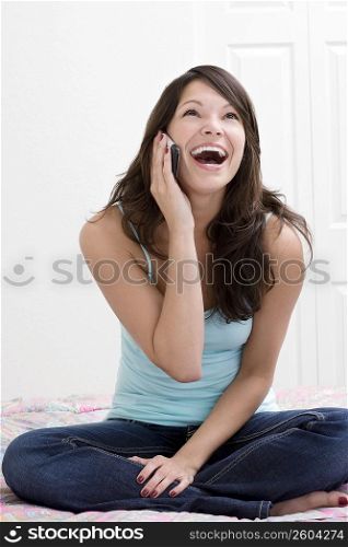 Young woman sitting on the bed and talking on a mobile phone