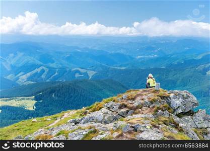 Young woman sitting on the cliff. Young woman sitting on the cliff and looking at mountain landscape