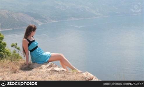 young woman sitting on the edge of a cliff near the Black Sea