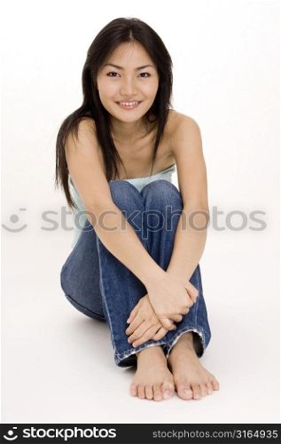 Young woman sitting on the floor and hugging her knees