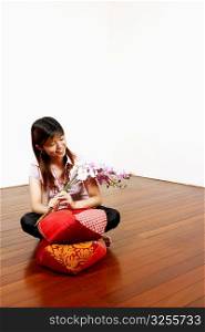 Young woman sitting on the floor and looking at flowers