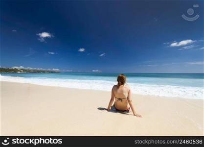 Young woman sitting on the sand from a tropical beach