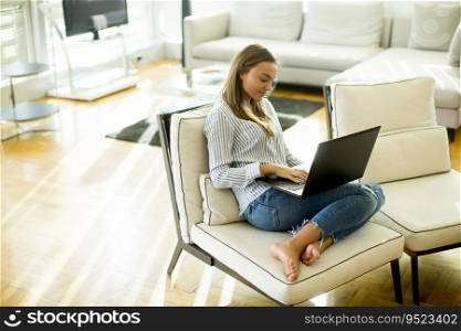 Young woman sitting on the sofa in the room and using laptop