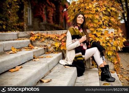 Young woman sitting on the steps outside in autumn day