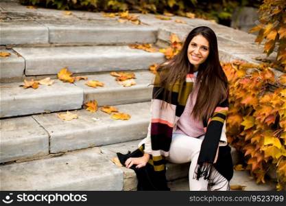 Young woman sitting on the steps outside in autumn day