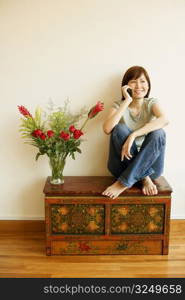 Young woman sitting on the table and talking on a mobile phone