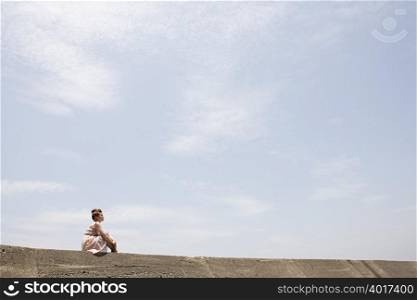 Young woman sitting on wall