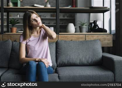 young woman sitting sofa having neck pain