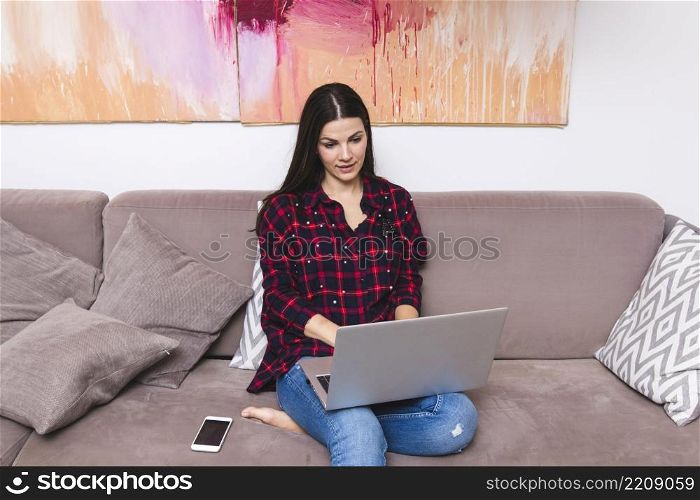 young woman sitting sofa using laptop home