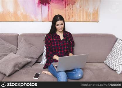 young woman sitting sofa using laptop home