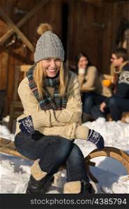 Young woman sitting winter snow sledge cottage spending holiday friends
