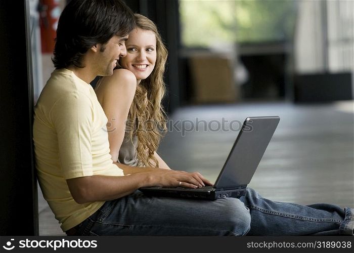 Young woman sitting with a young man working on a laptop