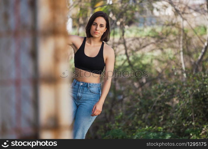 Young woman skater grabs ancient metal fence in a ancient industrial street, freedom concept