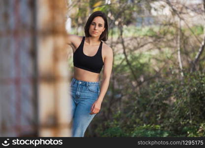 Young woman skater grabs ancient metal fence in a ancient industrial street, freedom concept