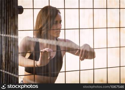 Young woman skater look inside through a fence in a ancient industrial street
