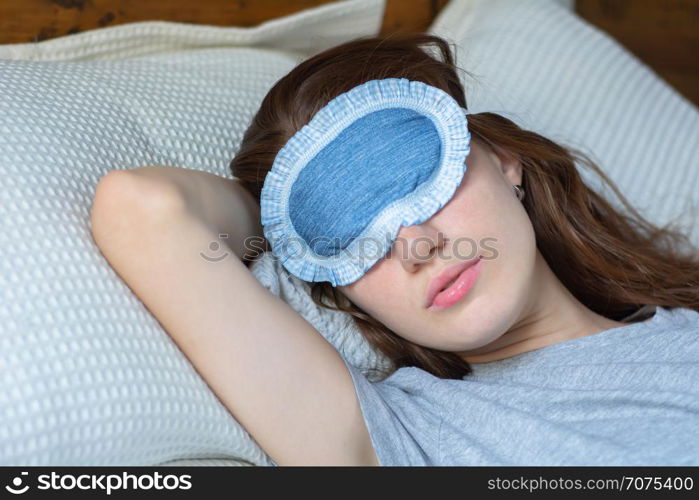 Young woman sleeping in bed with eye mask.