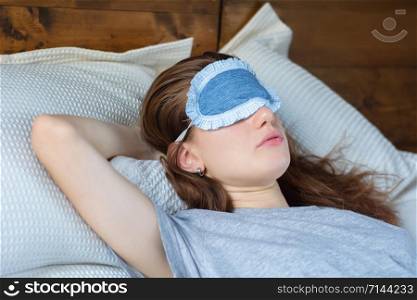 Young woman sleeping in bed with eye mask.
