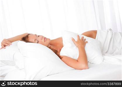 Young woman sleeping in white bed with pillow