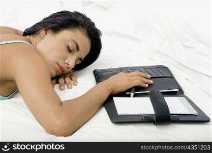 Young woman sleeping on a bed with a personal organizer