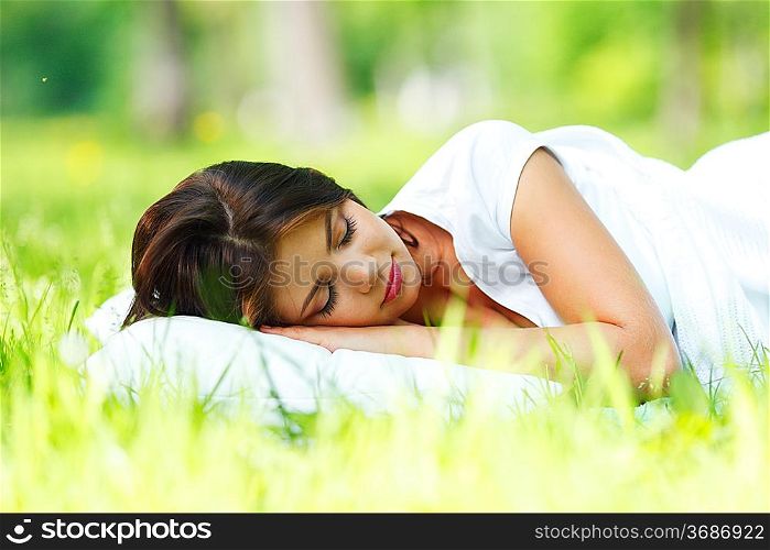 Young woman sleeping on soft pillow in fresh spring grass