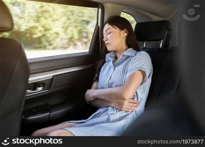 young woman sleeping while sitting in the back seat of car