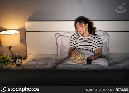 young woman sleeping while watching tv on a bed at night