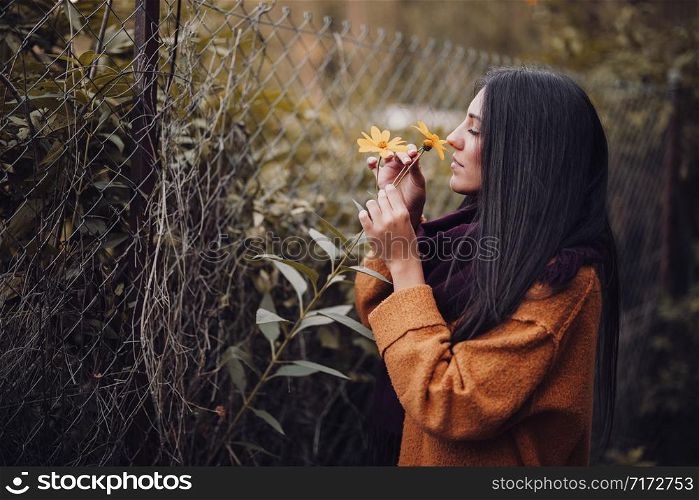 Young woman smelling a yellow flower in the field