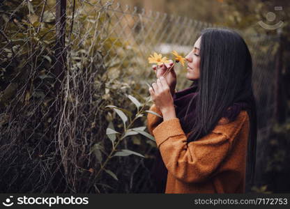 Young woman smelling a yellow flower in the field