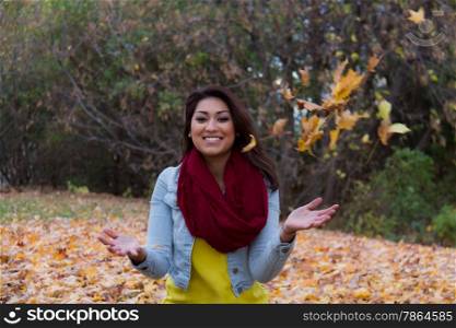 Young woman smiling and holding autumn leaves