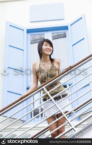 Young woman smiling and standing beside a railing